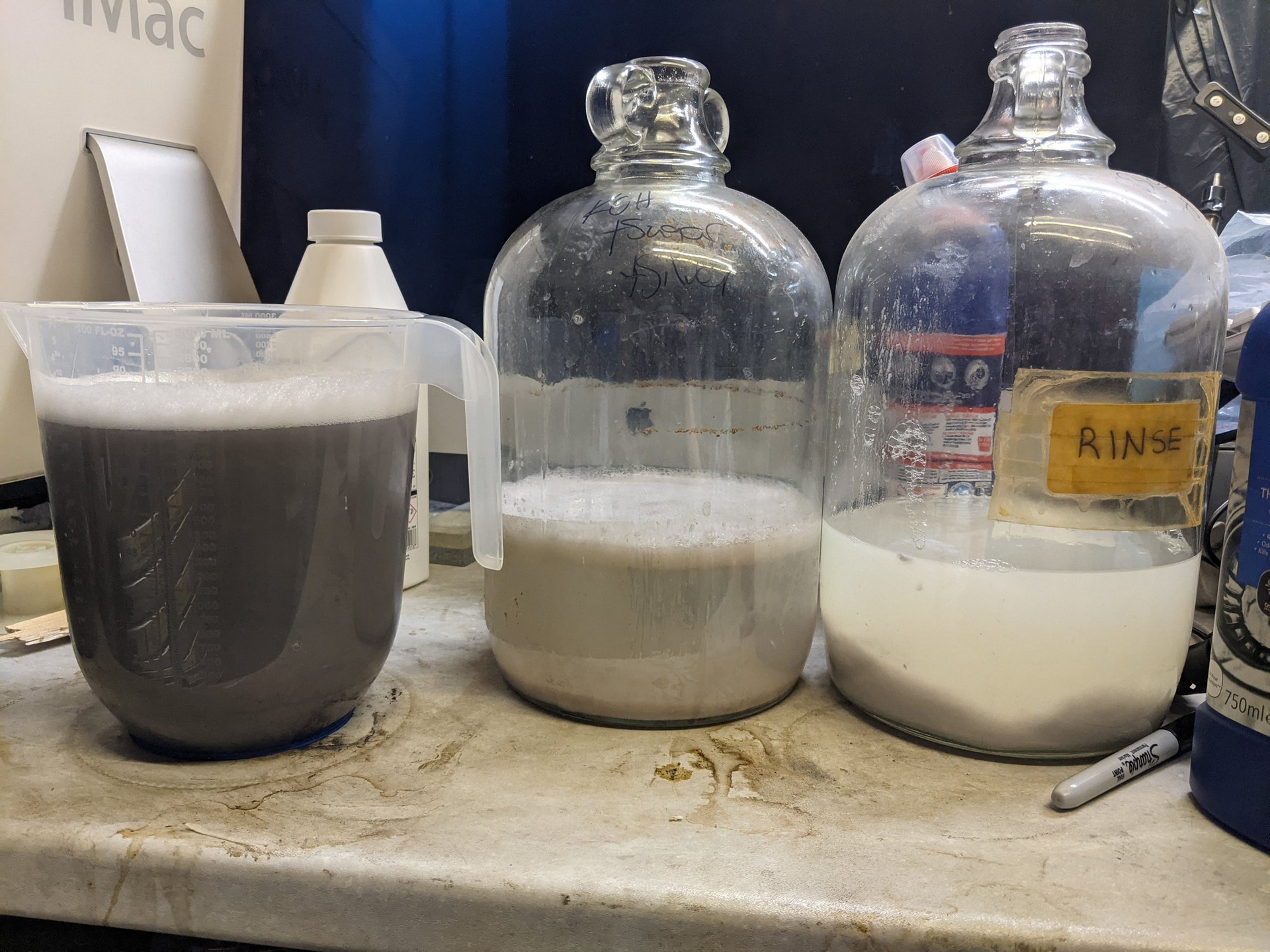 Three containers of bleach solution, the rightmost has most of the silver chloride precipitated out